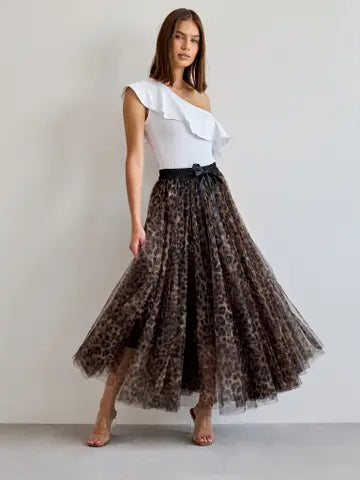 Woman wearing a white top and leopard print skirt on a plain background