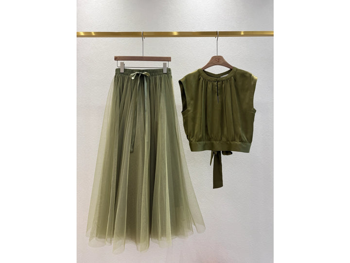 Green sleeveless top and tulle skirt on hangers against a white background
