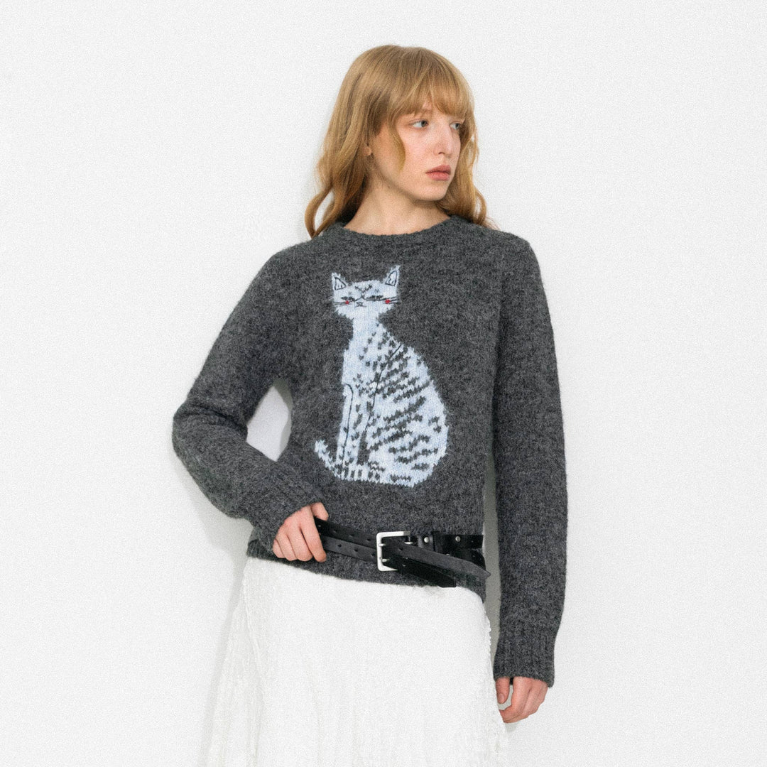 Woman wearing a gray sweater with a cat design on a white background