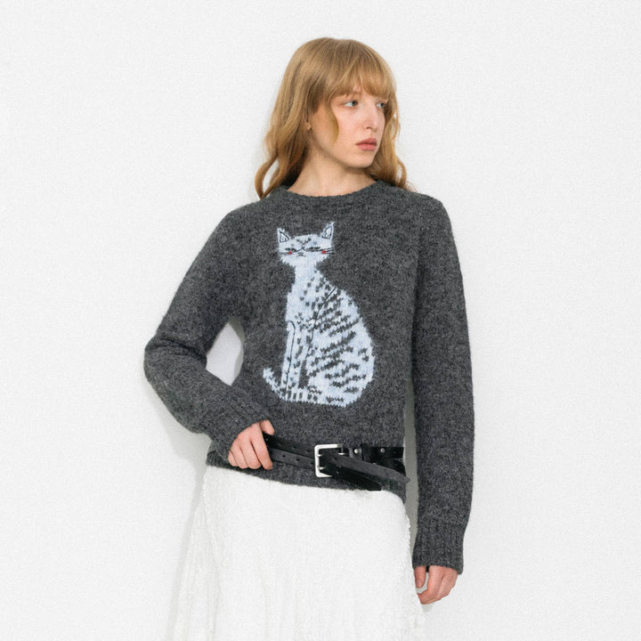 Woman wearing a gray sweater with a cat design on a white background