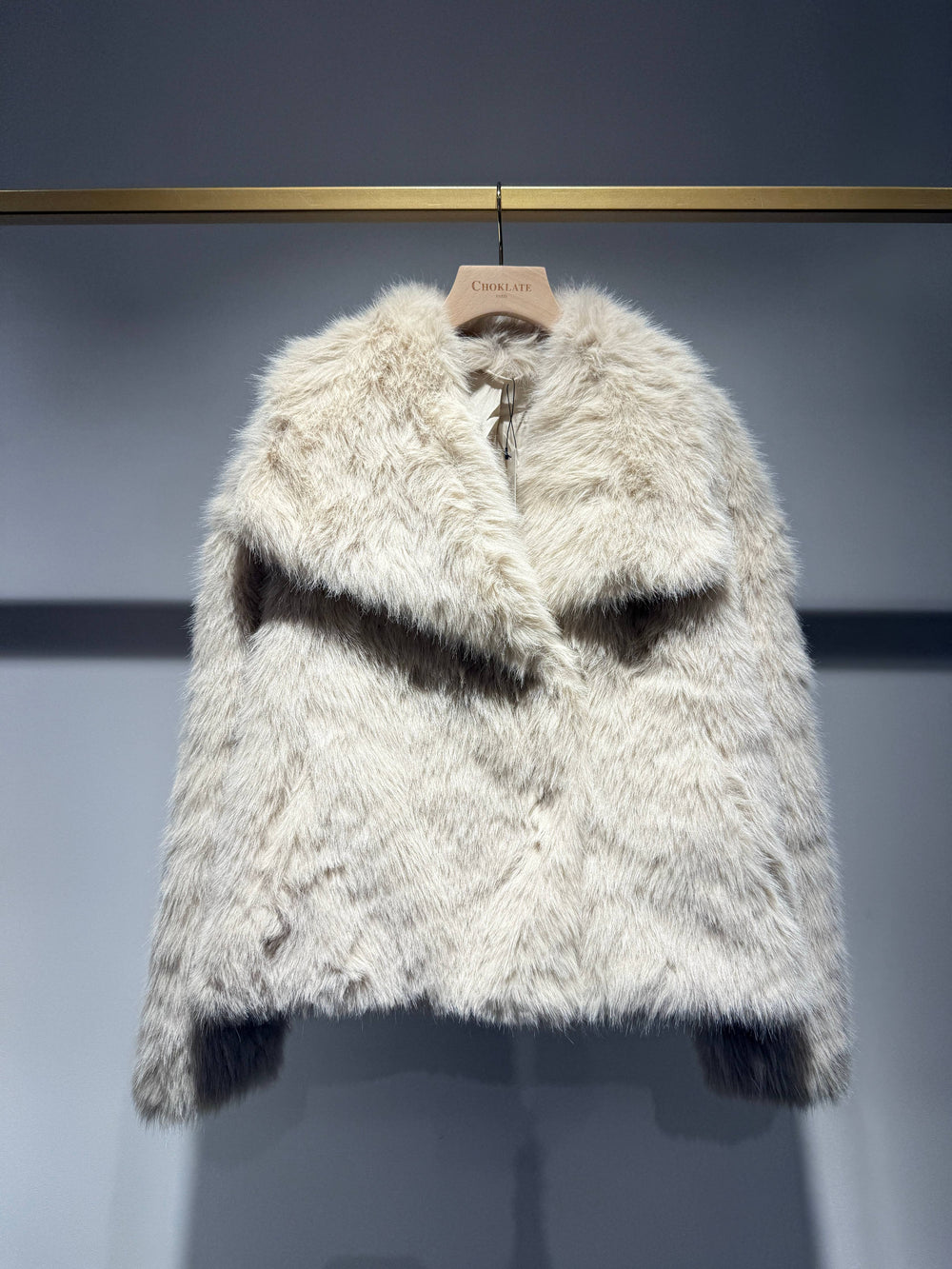 Furry white coat on a hanger against a gray background