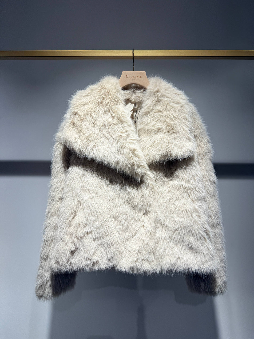 Furry white coat on a hanger against a gray background