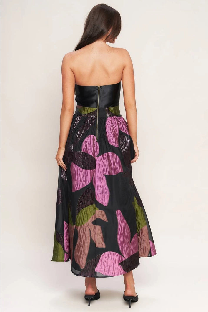 Woman wearing a strapless dress with floral pattern on a plain background