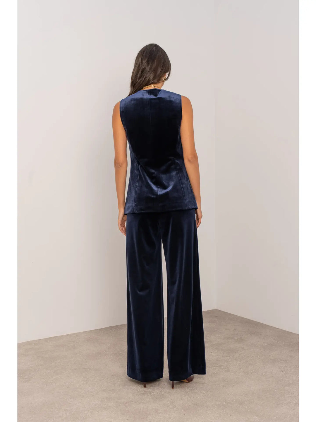 Person wearing a navy velvet outfit with wide-leg pants against a plain background