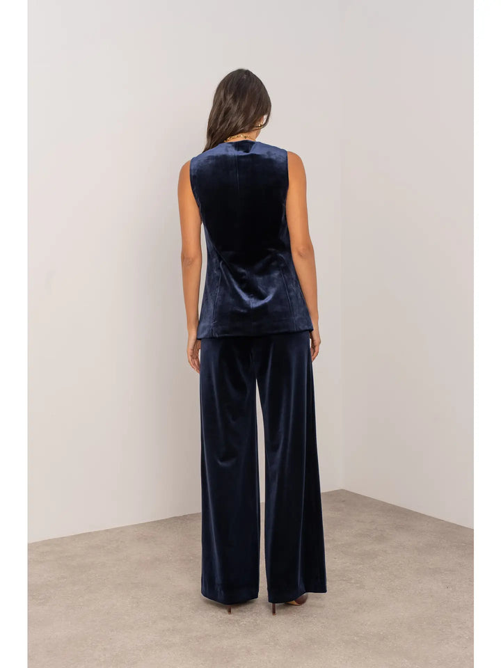 Person wearing a navy velvet outfit with wide-leg pants against a plain background