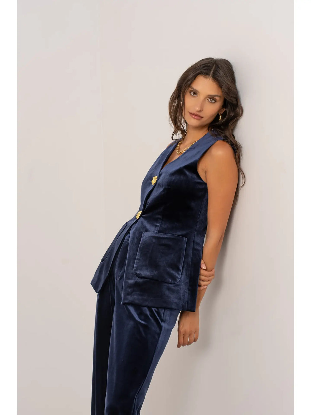 Woman wearing a navy velvet suit against a plain background