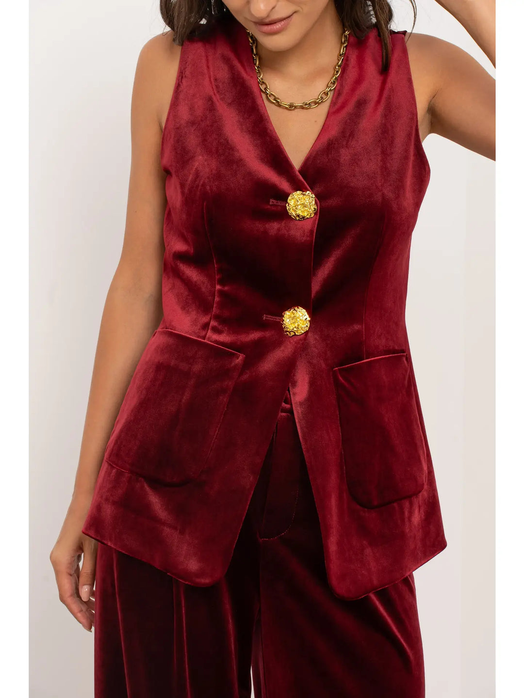 Red velvet blazer with gold buttons worn by a person on a white background