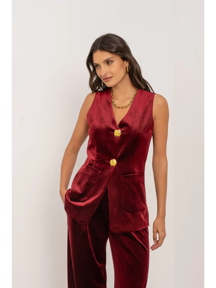 Woman wearing a red velvet suit with gold buttons on a white background