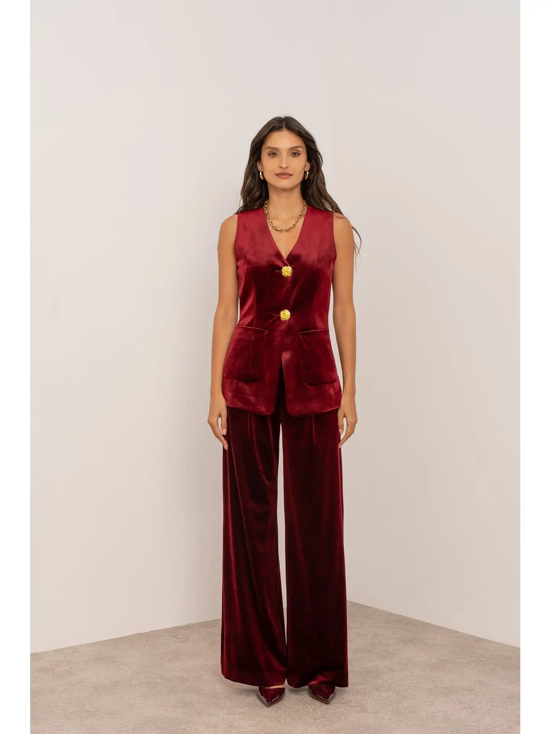 Woman wearing a burgundy velvet outfit with a plain background