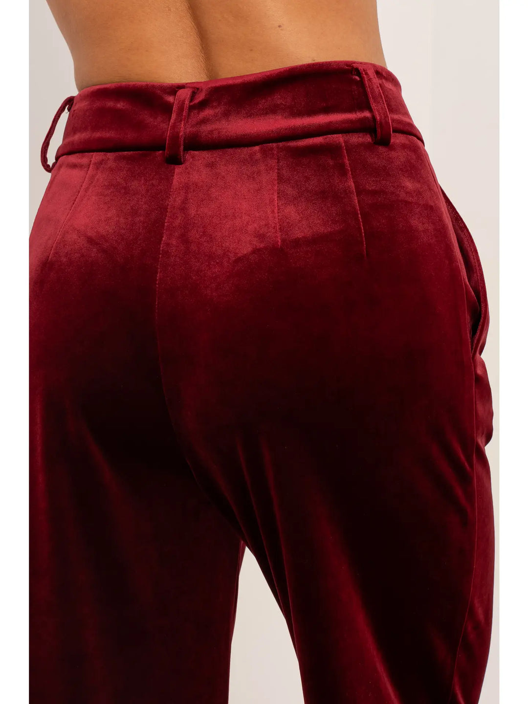 Maroon velvet pants with a belt on a plain background