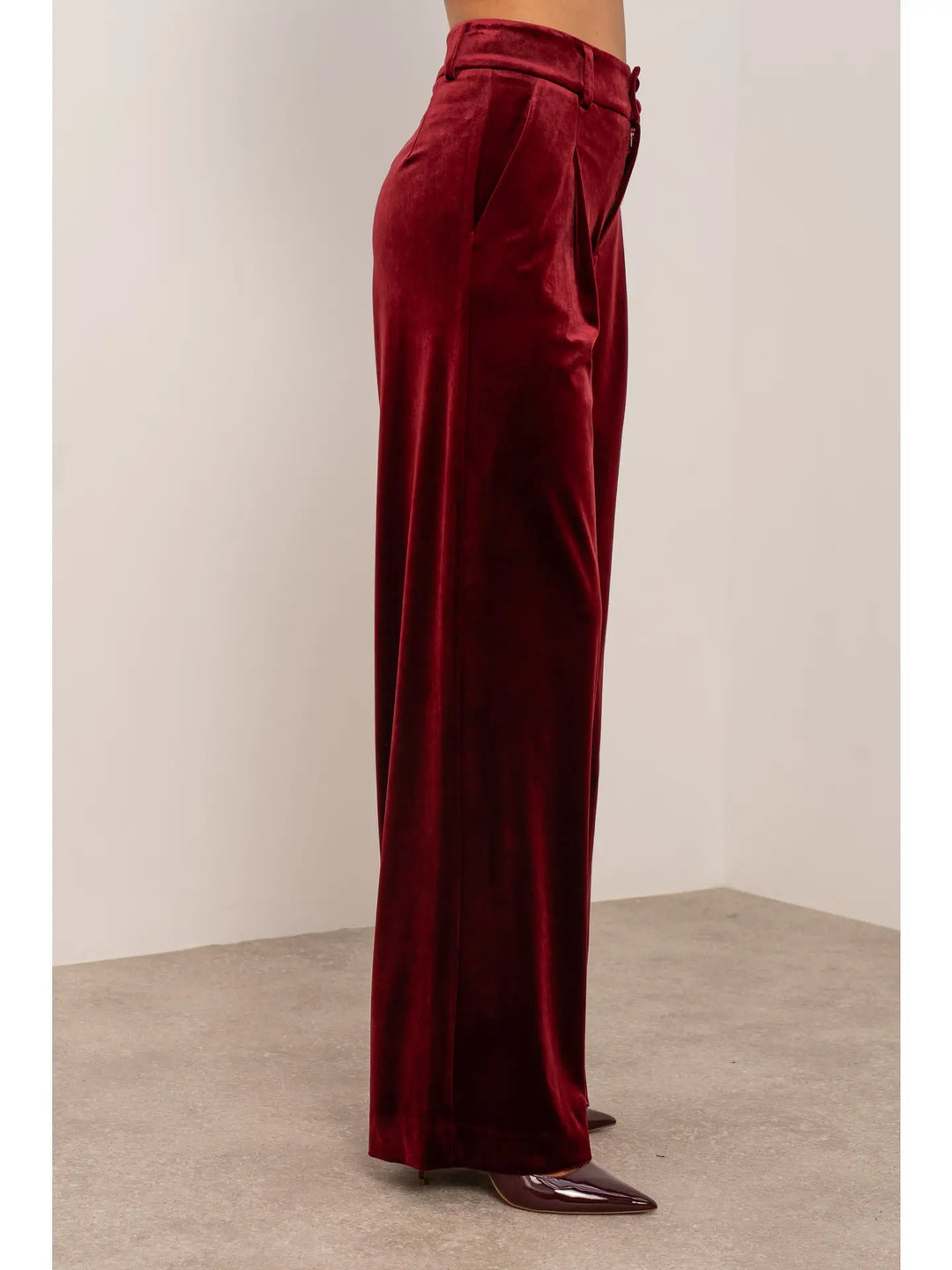 Maroon velvet pants worn by a person on a plain background