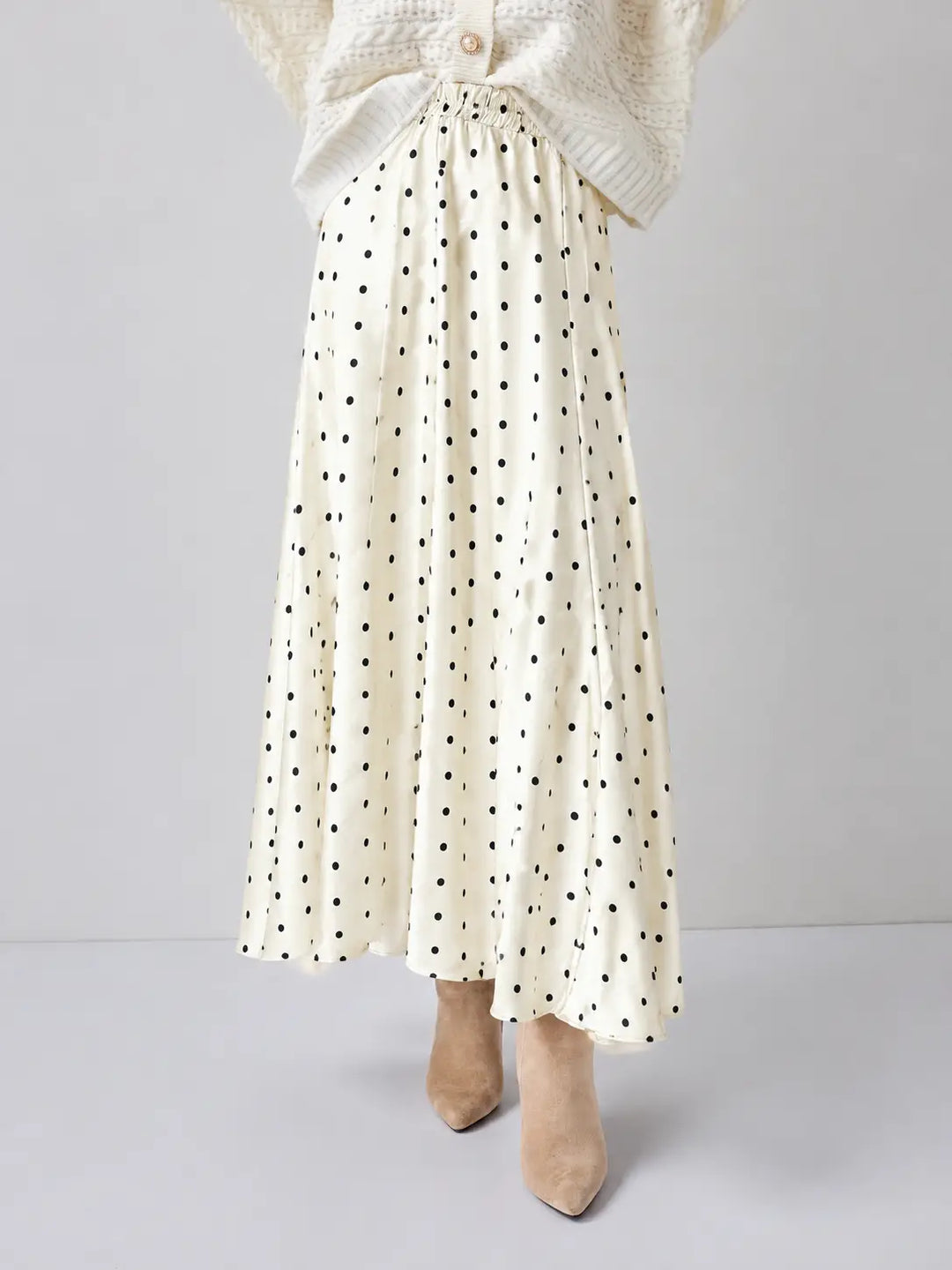White polka dot skirt worn with a white cardigan on a light gray background