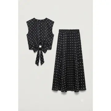 A two-piece women's outfit set featuring a sleeveless black top with white polka dots and a matching tie-front waist, paired with a matching black midi skirt with white polka dots, displayed on a light gray background.