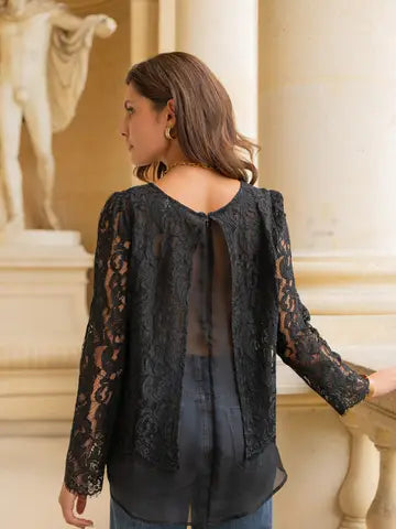 Woman wearing a black lace top in an elegant indoor setting