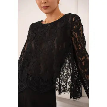 Black lace top worn by a person on a white background