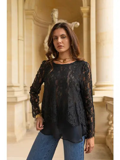 Woman wearing a black lace top and blue jeans in an elegant interior setting