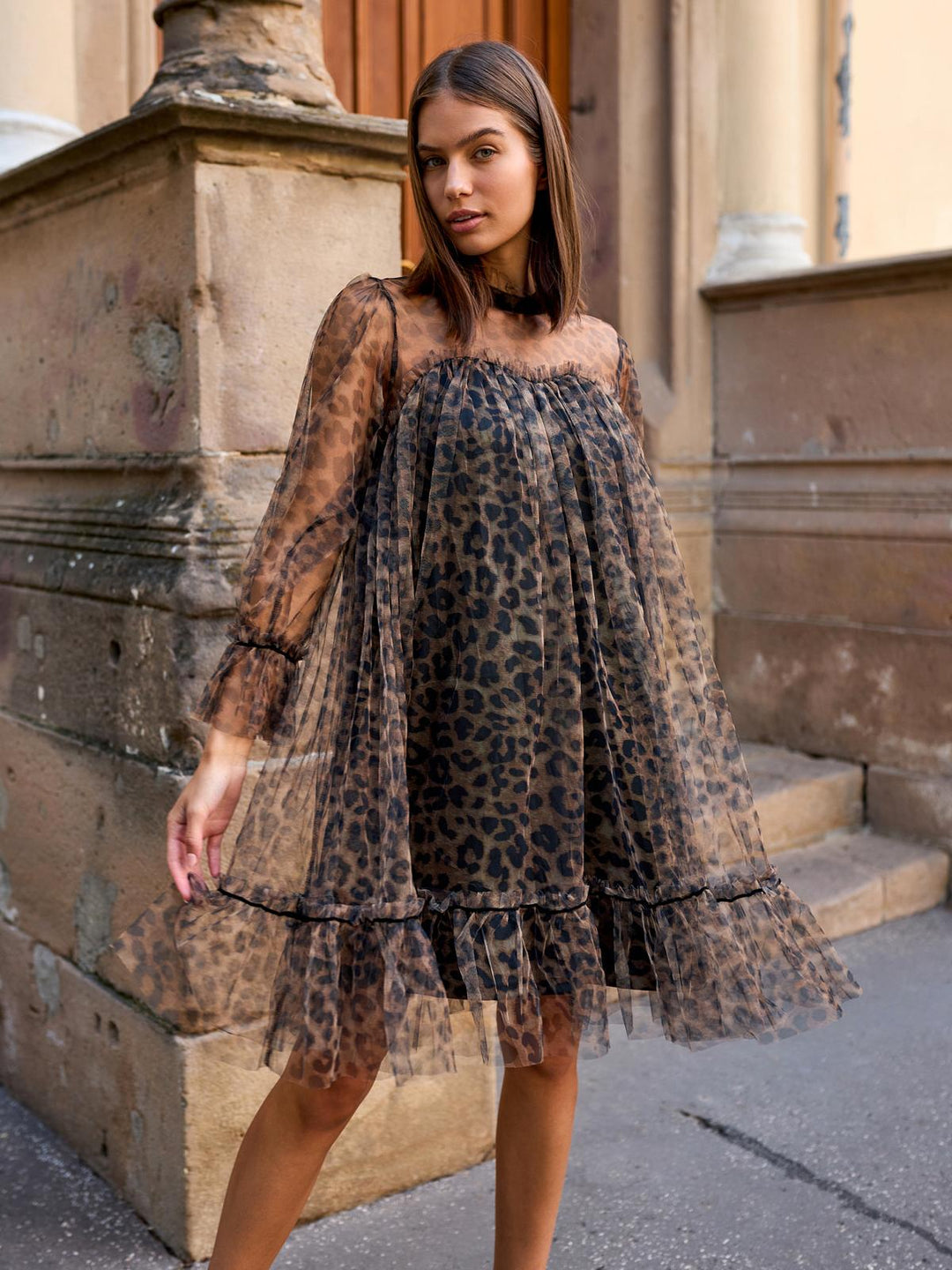 Woman wearing a leopard print dress standing outdoors.