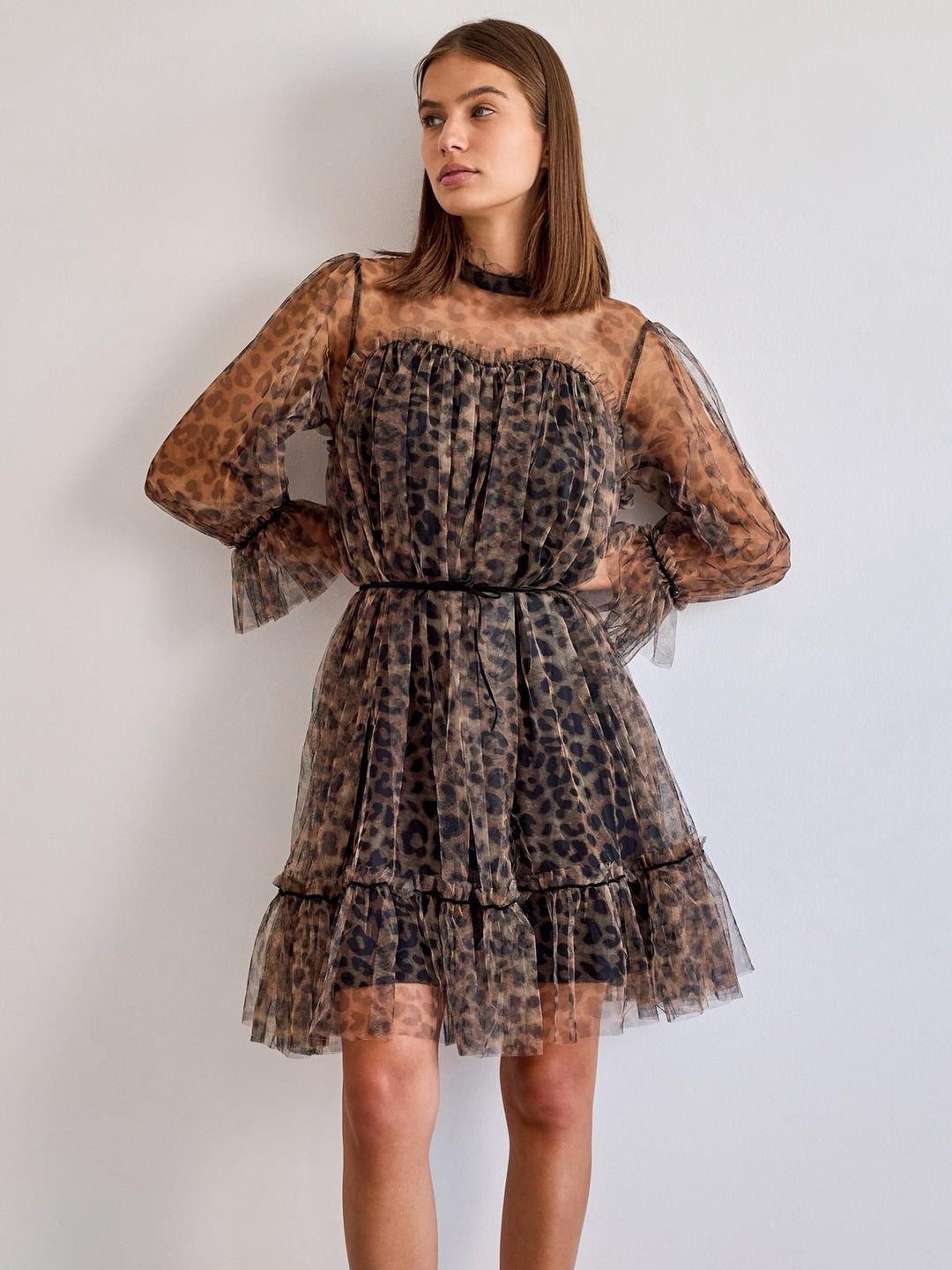 Woman wearing a leopard print dress against a plain background