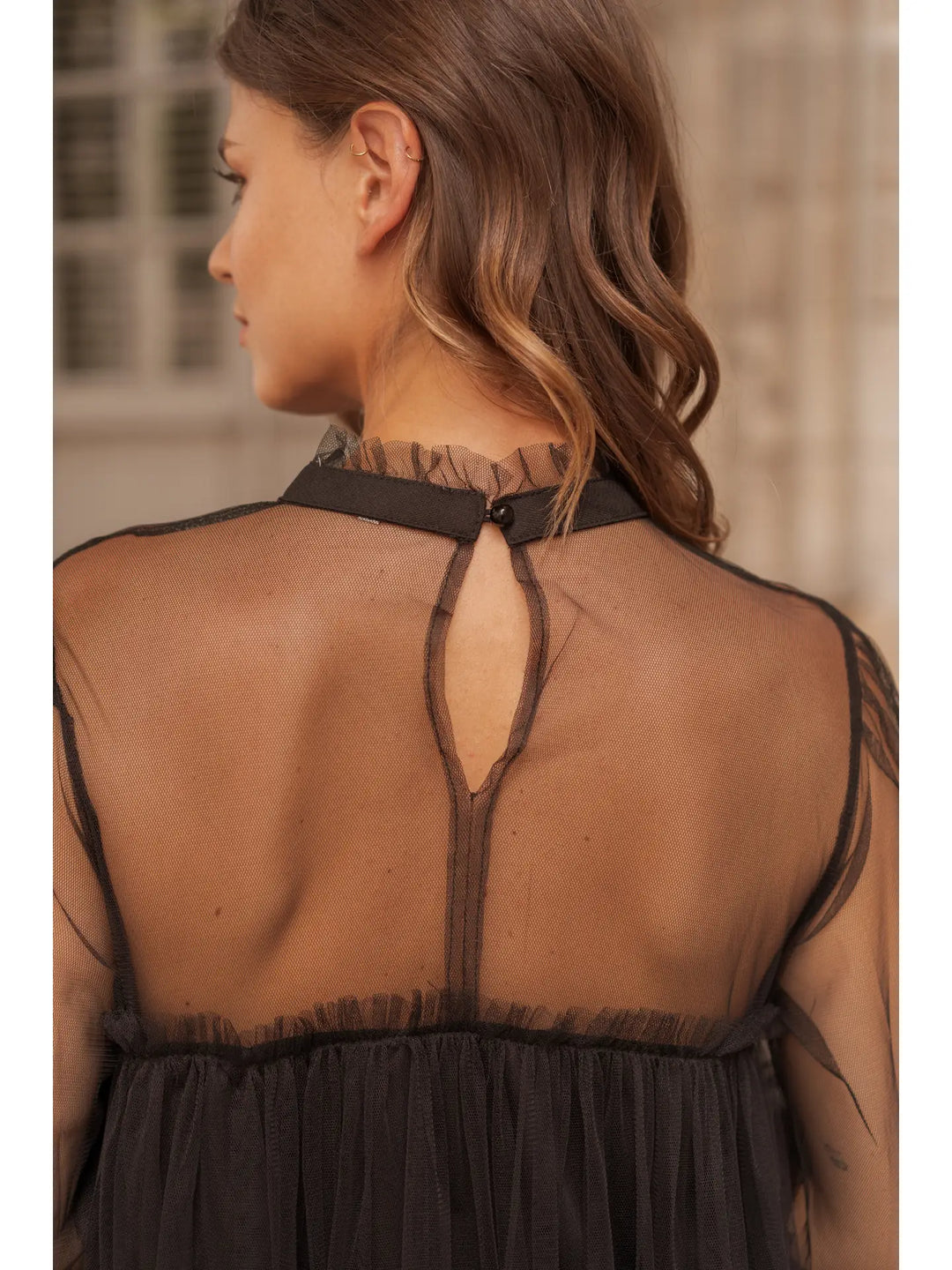 Woman wearing a black sheer dress with a blurred background