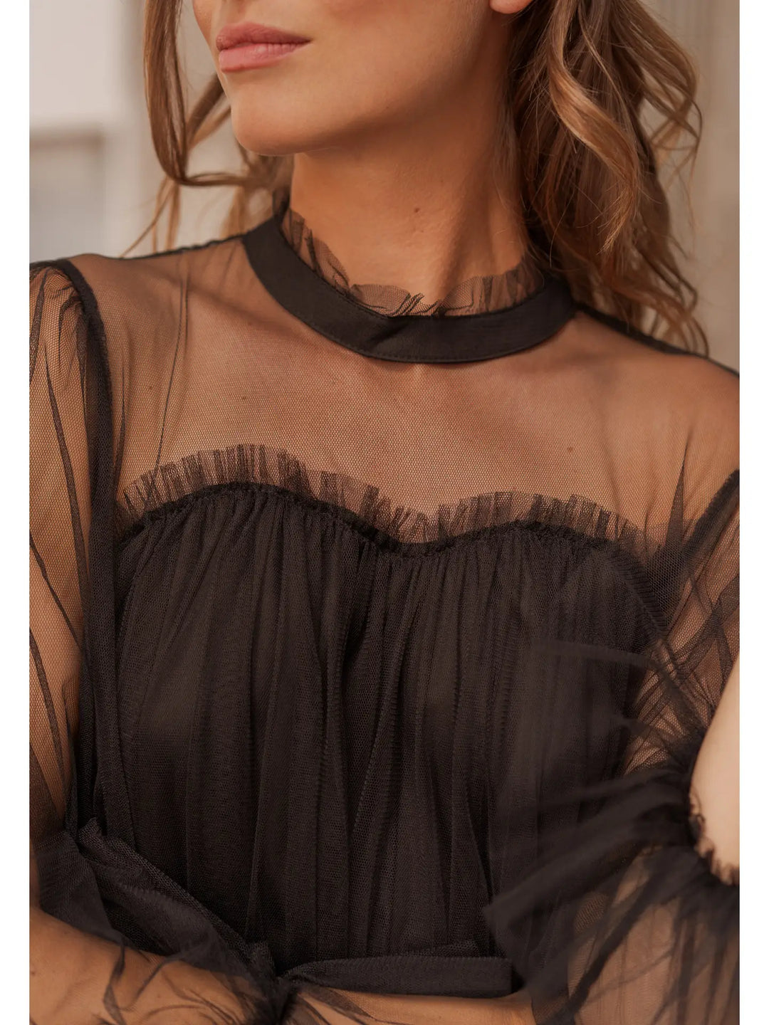 Close-up of a person wearing a sheer black top with a blurred background