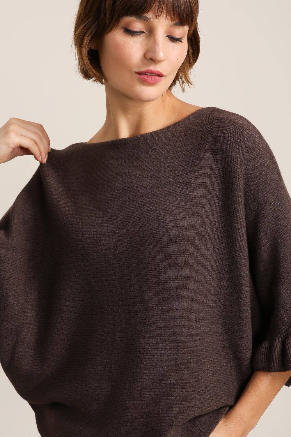 Woman wearing a brown sweater against a plain background