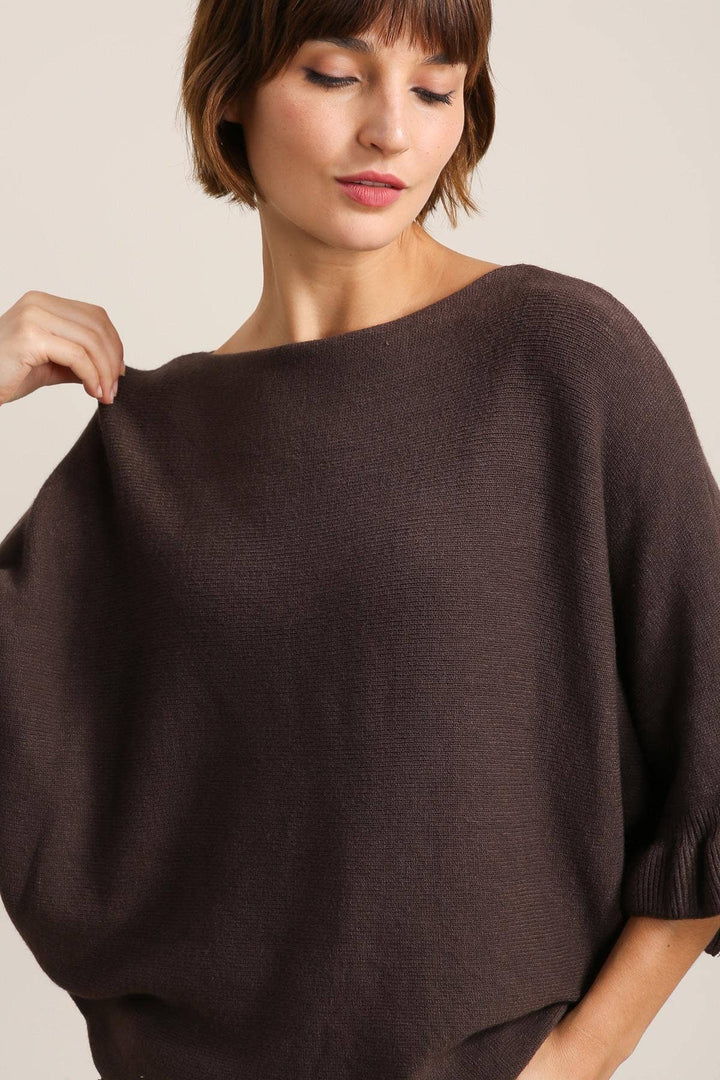 Woman wearing a brown sweater against a plain background