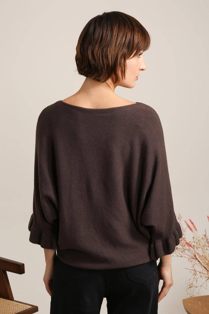 Woman wearing a brown sweater against a neutral background