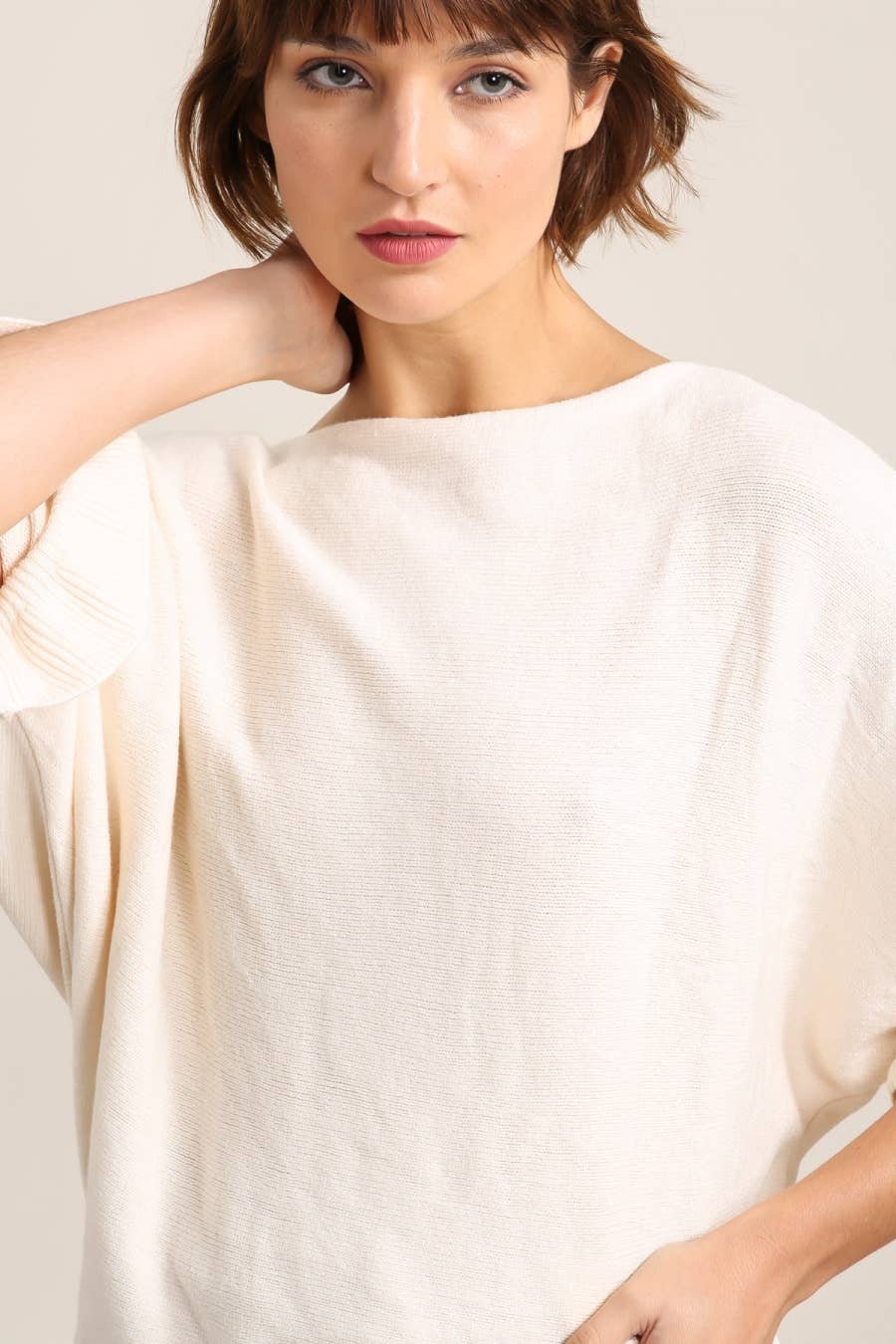 Woman wearing a white top against a plain background