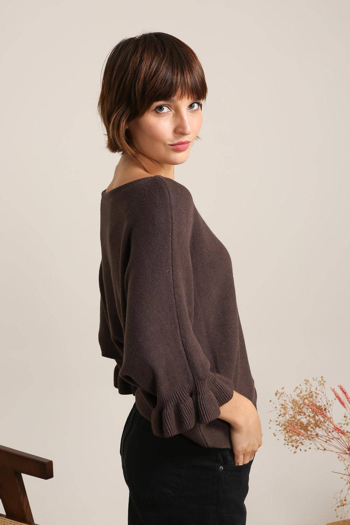 Woman wearing a brown sweater against a plain background