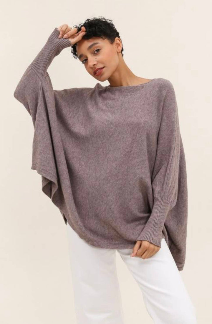 Woman wearing a loose-fitting purple sweater against a plain background