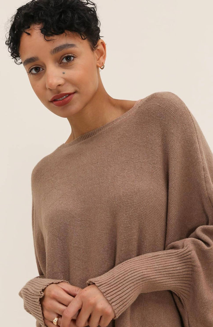 Woman wearing a brown sweater against a plain background