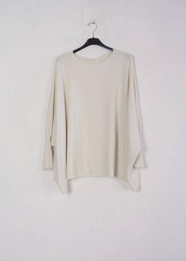 Beige long-sleeve top on a hanger against a white background