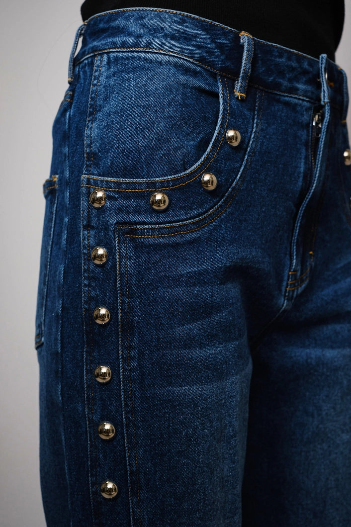 Close-up of blue jeans with decorative buttons on a gray background