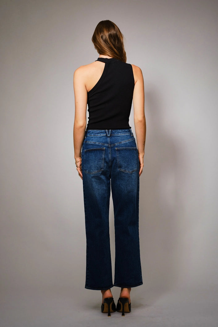 Person wearing blue jeans and a black sleeveless top against a gray background