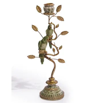 An ornate metal candlestick holder shaped like a tree branch with gold-toned leaves and a green glazed bird figurine perched on one branch, set against a plain white background.