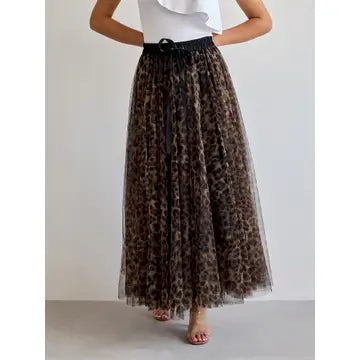 A model wearing a leopard print tulle maxi skirt with a black waistband and drawstring, paired with a white ruffled top, shown against a plain light gray background.