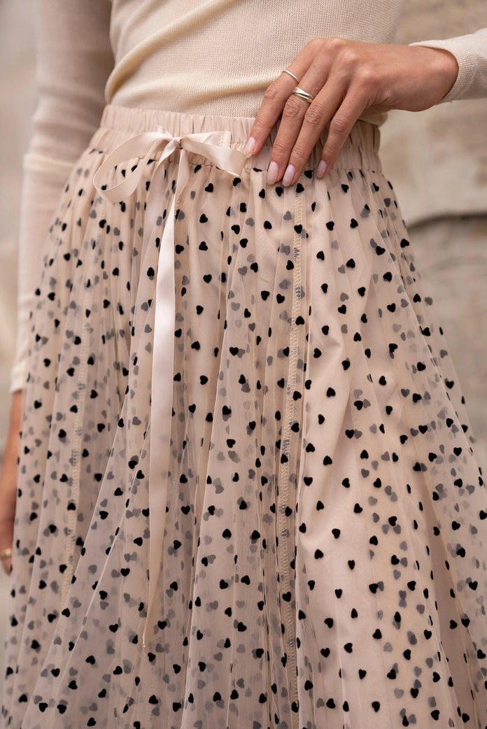 Beige tulle skirt with black heart pattern worn by a person.