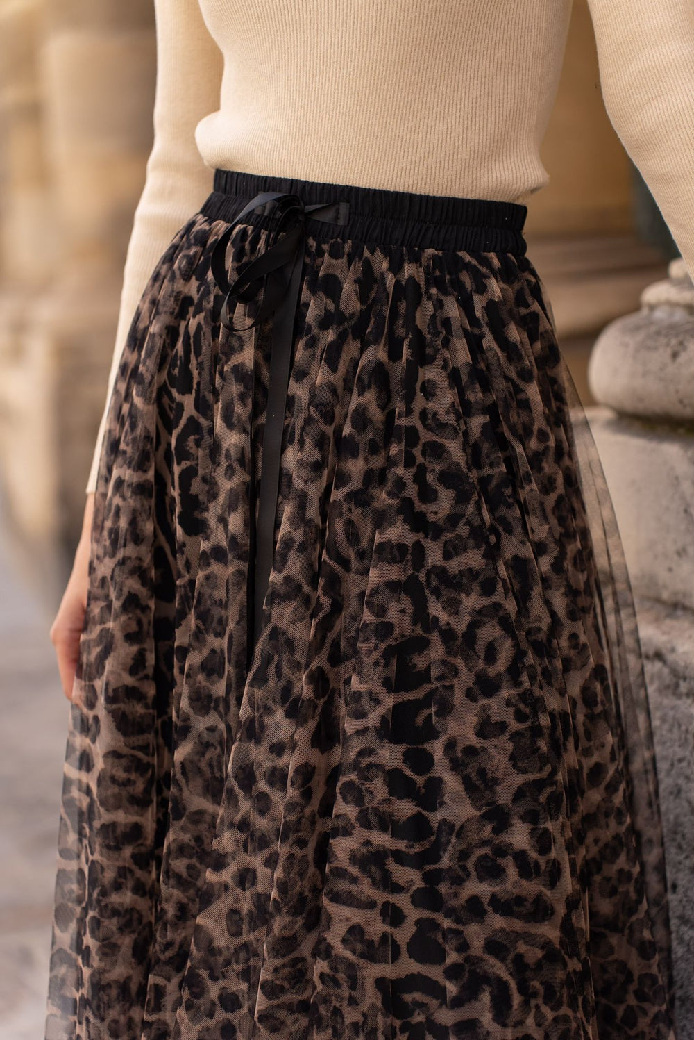 Leopard print skirt worn with a beige top against an outdoor background
