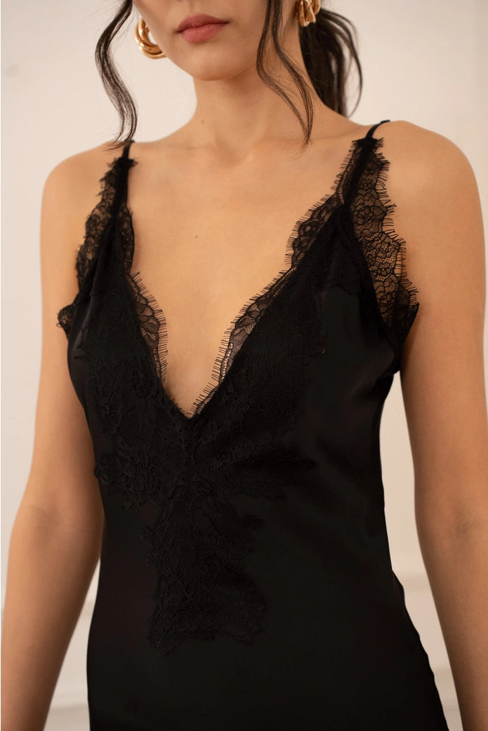 Black lace-trimmed dress worn by a model against a neutral background
