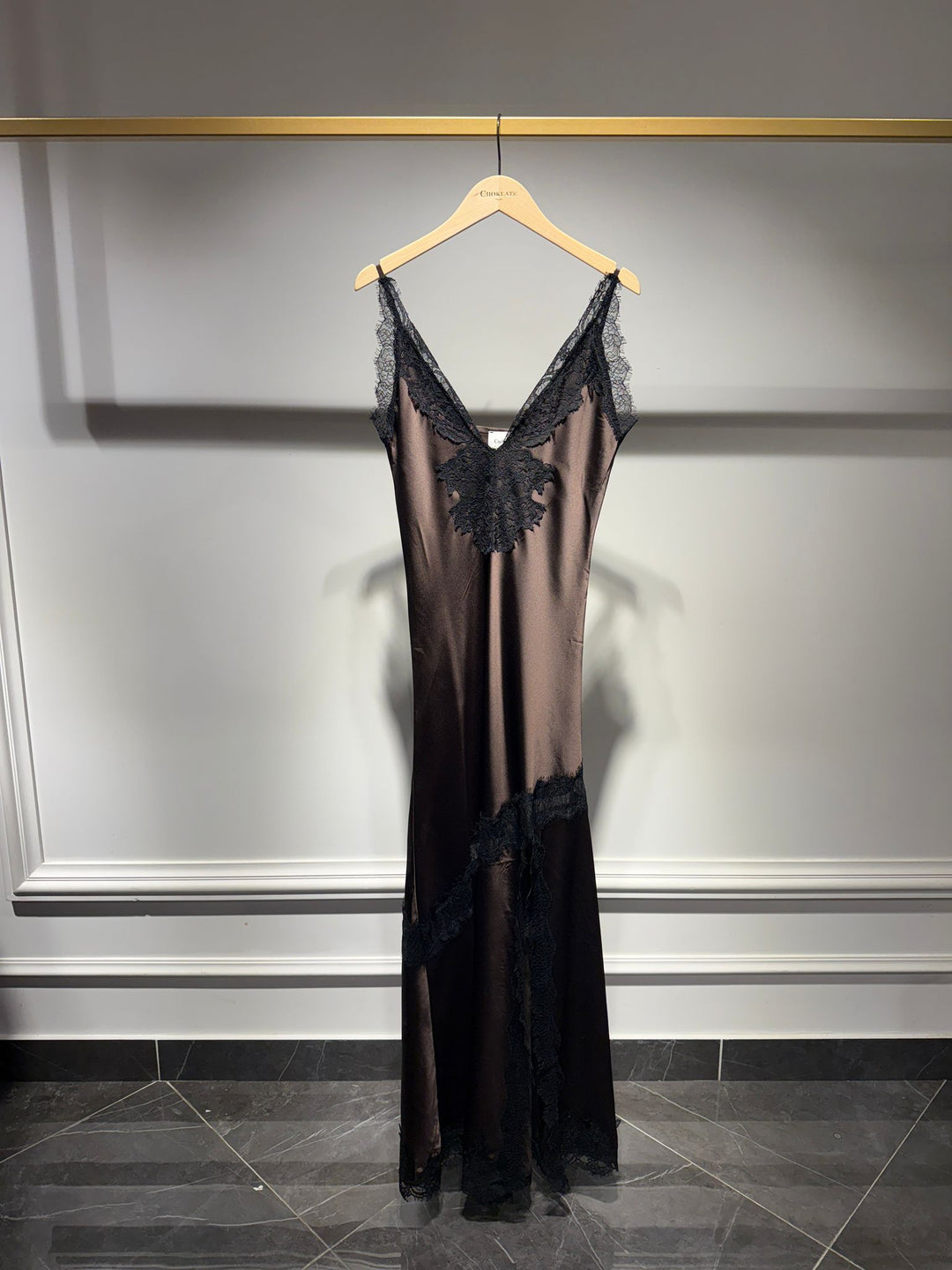 Black lace nightgown on a hanger against a gray wall.