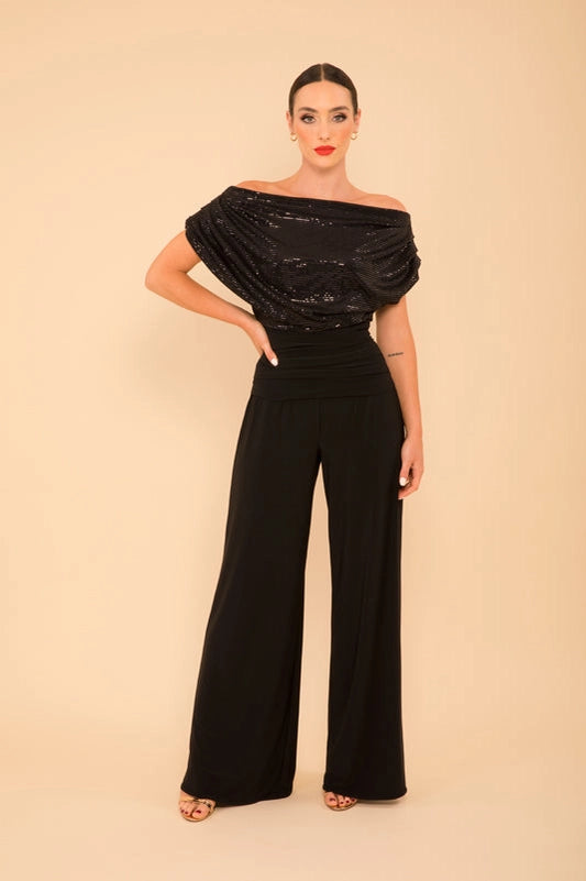 Woman wearing a black off-shoulder top and wide-leg pants on a beige background