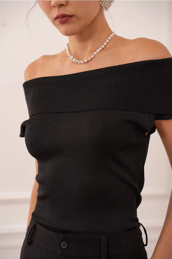 Black off-shoulder top worn by a person with a neutral background