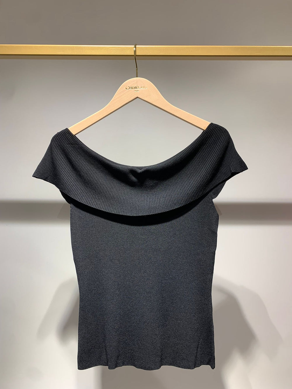 Black top on a hanger against a neutral background