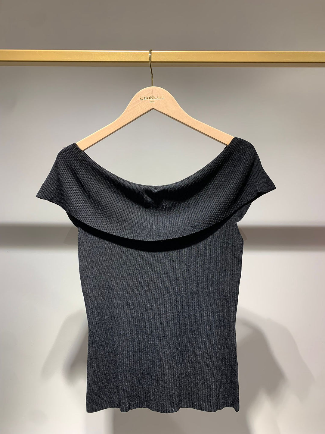 Black top on a hanger against a neutral background
