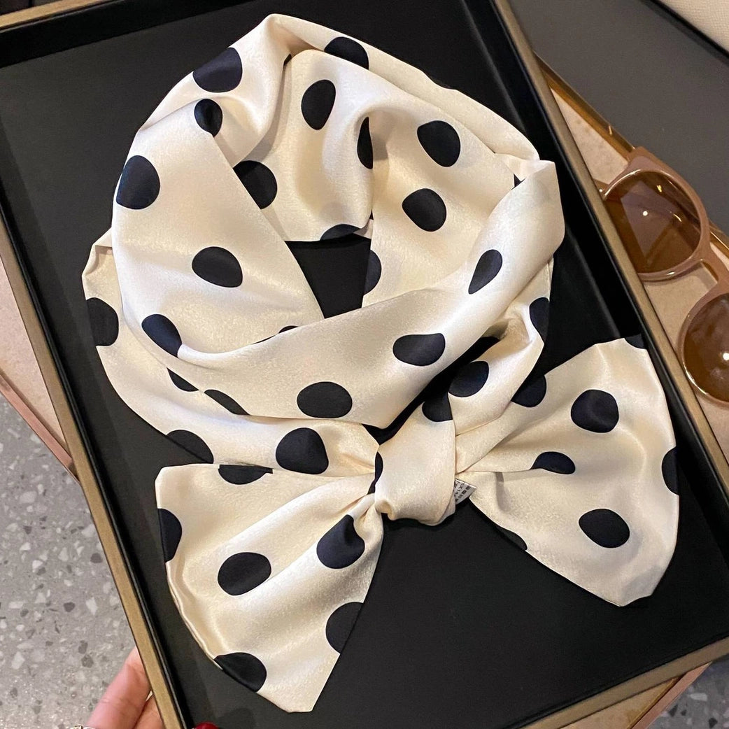 Beige scarf with black polka dots on a black tray