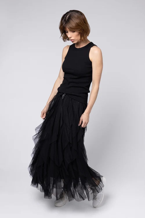 Woman wearing a black sleeveless top and layered black skirt on a white background