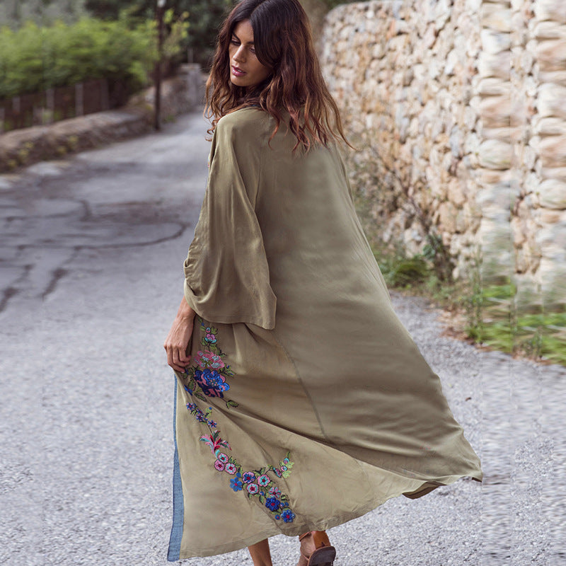 Woman wearing a long, embroidered dress walking on a stone path.