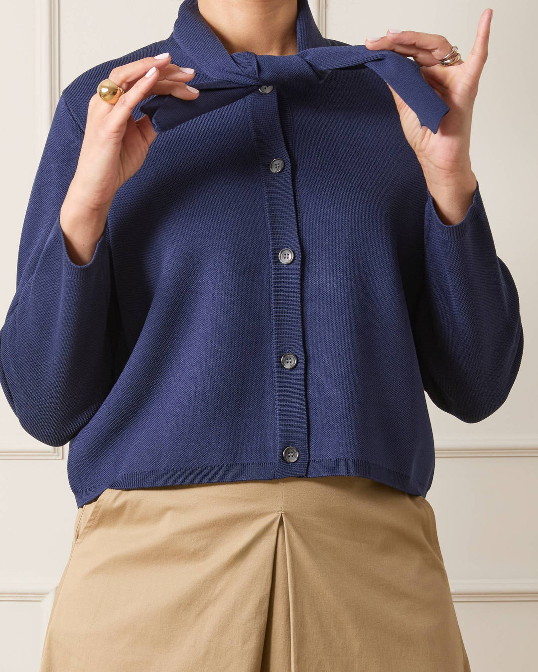 Navy blue cardigan with a bow detail worn by a person, against a neutral background