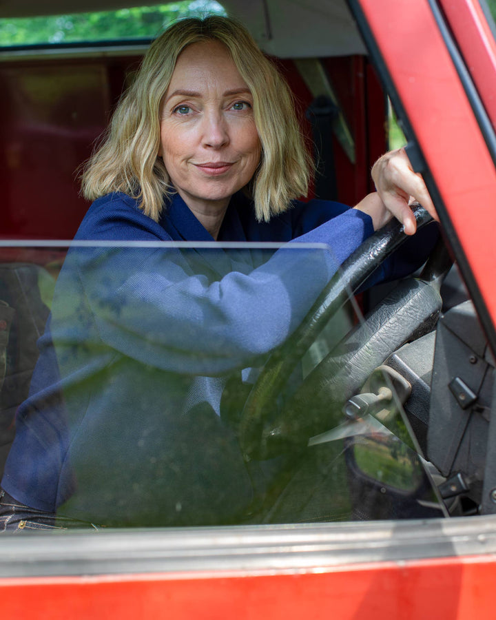 Woman sitting inside a red vehicle, looking out the window.