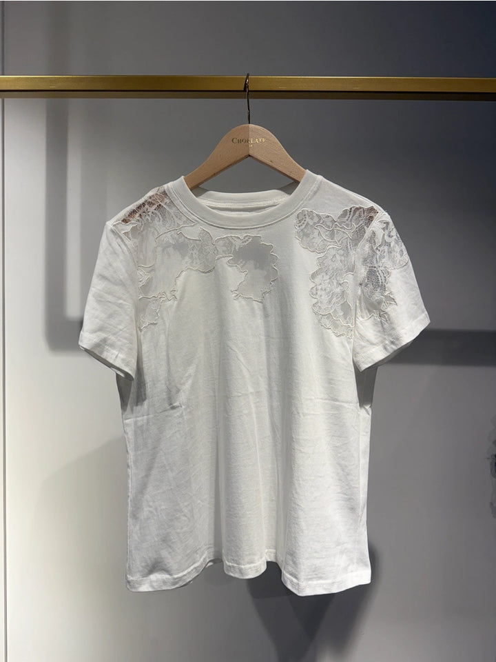 White lace top on a wooden hanger against a gray background